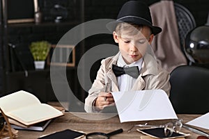 Cute little detective reading report indoors