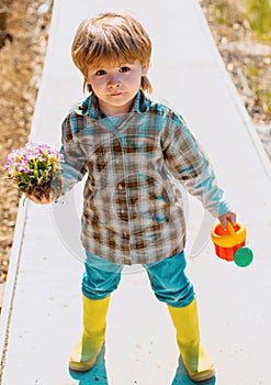 Cute little farmer working with spud on spring field. Child farmer in the farm with countryside background.