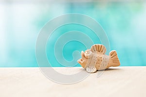 Cute little fish clay over blurred blue water background