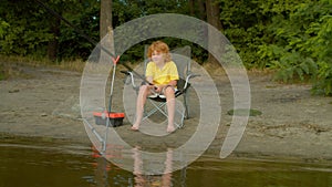 Cute little fisherman with fishing rod angling on lake