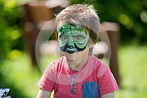 Cute little five years old boy,. having his face painted on his