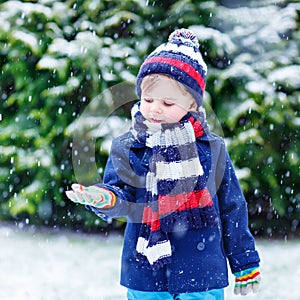 Cute little funny boy in colorful winter clothes having fun with