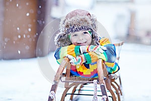 Cute little funny boy in colorful winter clothes having fun with