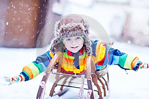 Cute little funny boy in colorful winter clothes having fun with