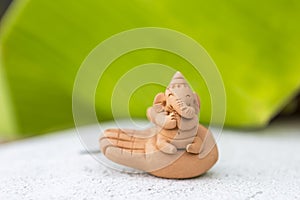 Cute little Ganesh clay sculpture with space on blurred green banana leaf background