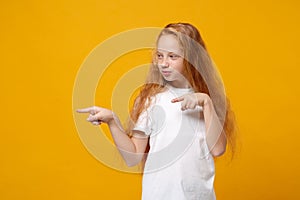 Cute little ginger kid girl 12-13 years old in white t-shirt isolated on yellow wall background children studio portrait