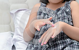 Cute little girl applying body lotion cream on hand