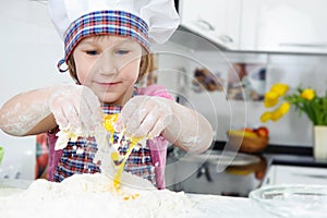 Cute little girl in apron cooking cookies