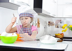 Cute little girl in apron whisking eggs