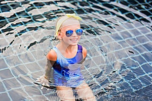 Cute little girl with a bandage on his head in the sun-colored glasses in the pool floating on a summer day.