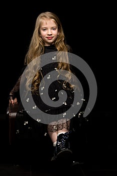 Cute little girl in a beautiful dress on a black background.