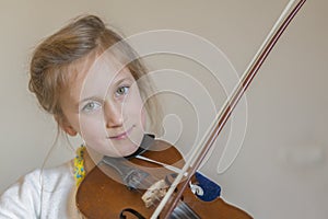 Cute little girl in a beautiful dress playing violin. Joyful and happy emotions. Training. Education. School. Aesthetic training.