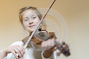 Cute little girl in a beautiful dress playing violin. Joyful and happy emotions. Training. Education. School. Aesthetic training.