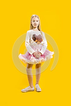 Cute little girl in a beautiful festive dress on a yellow background. Teenager going to a party.