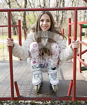 Cute little girl with a beautiful smile on roller skates posing in the park