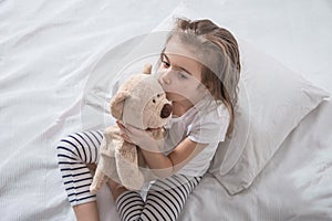 Cute little girl in bed with soft toy