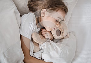 Cute little girl in bed with soft toy