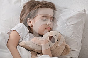 Cute little girl in bed with soft toy