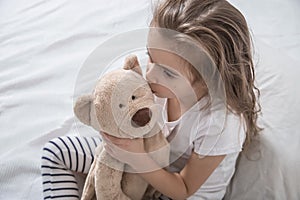 Cute little girl in bed with soft toy