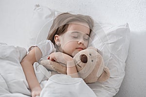 Cute little girl in bed with soft toy