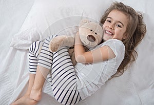 Cute little girl in bed with soft toy