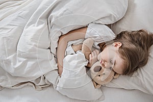 Cute little girl in bed with soft toy