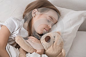 Cute little girl in bed with soft toy