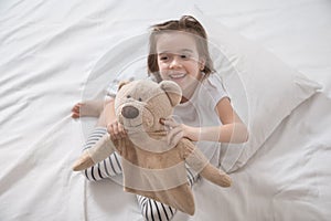 Cute little girl in bed with soft toy