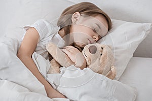 Cute little girl in bed with soft toy