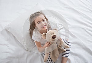 Cute little girl in bed with soft toy