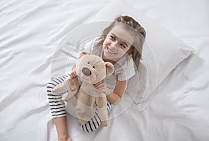 Cute little girl in bed with soft toy