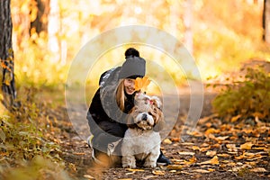 Cute little girl in a black coat with a dog walk in the park. A child is training a dog. Faithful friends of man. Leisure with