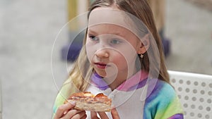 cute little girl blonde eats a slice of pizza. a traditional and delicious dish.