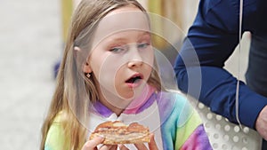 cute little girl blonde eats a slice of pizza. a traditional and delicious dish.