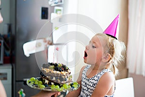 Cute little girl blowing candles on her birthday cake