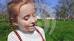 Cute little girl blowing dandelion flower outdoors. Happy child having fun in spring park.