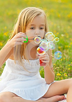 Cute little girl blowing soap bubbles