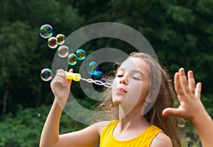 Cute Little Girl blowing soap bubbles outdoor at summer day - ha