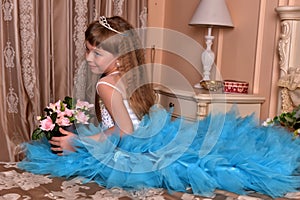 Cute little girl in a blue dress sitting