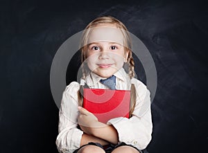 Cute little girl with book. Happy Child on empty blackboard