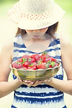 Cute little girl with bowl full of fresh strawberries. Pre - teen girl with glasses and teeth - dental braces