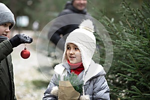 Cute little girl and boy with dad decorate a Christmas tree outside