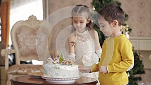 Cute little girl and boy lay sweet snowflakes on a Christmas cake. beautiful children in a spacious and bright room near
