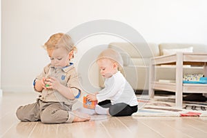 Cute little girl and boy playing with toys at home