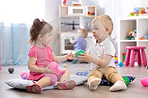 Cute little girl and boy playing with toys in playroom