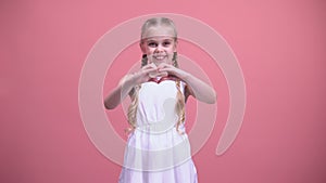 Cute little girl with braids showing heart gesture, charity, children adoption