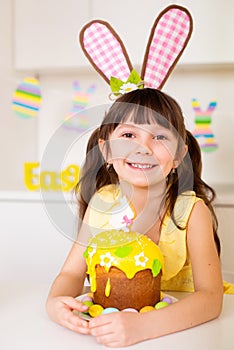 A cute little girl with bunny ears prepares an Easter cake and painted eggs. Religious holiday