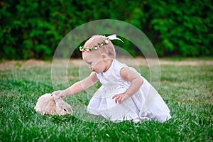 Cute little girl with a bunny rabbit has a easter at green grass