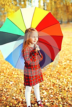 Cute little girl child with colorful umbrella in sunny autumn da