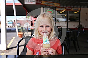 Cute Little Girl Child Eating Ice Cream at Diner on Summer Day